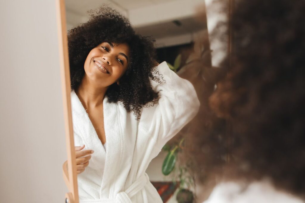 Happy woman with curly hair smiling in a bathrobe at home.
